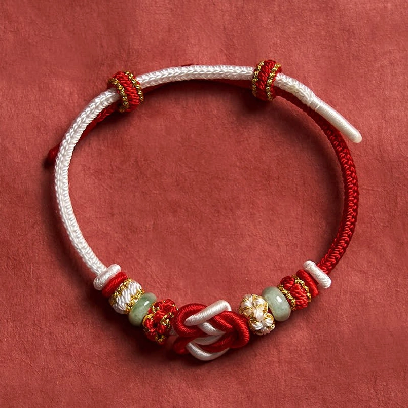Red string jade prosperity bracelet showing adjustable slide knot mechanism