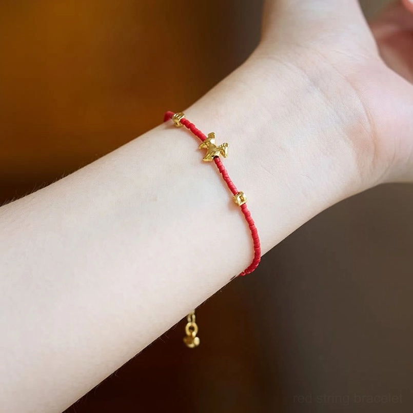 Worn Year of the Horse red liuli bracelet on slim wrist over wooden table background