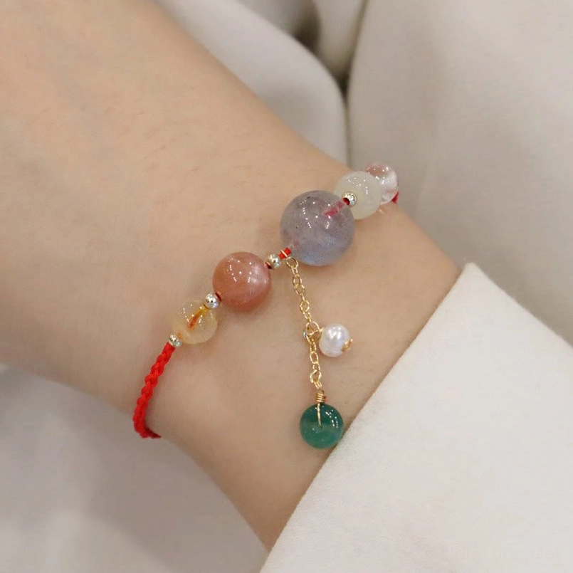 Woman wearing red string moonstone healing bracelet on wrist side view natural fit