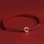 Red braided peace buckle bracelet with gold circular charm displayed on dark background