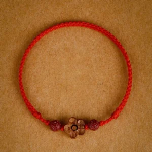 Red peach blossom cinnabar bracelet with braided red string and carved peach wood flower charm