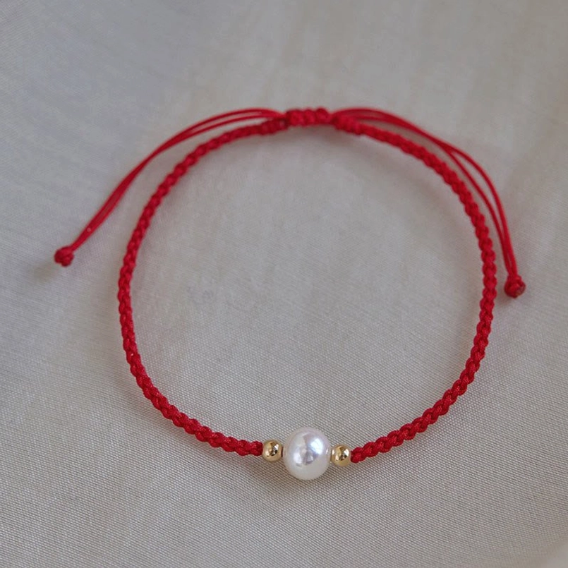 Red pearl string bracelet flat lay dual pull cord closure white pearl gold bead accents