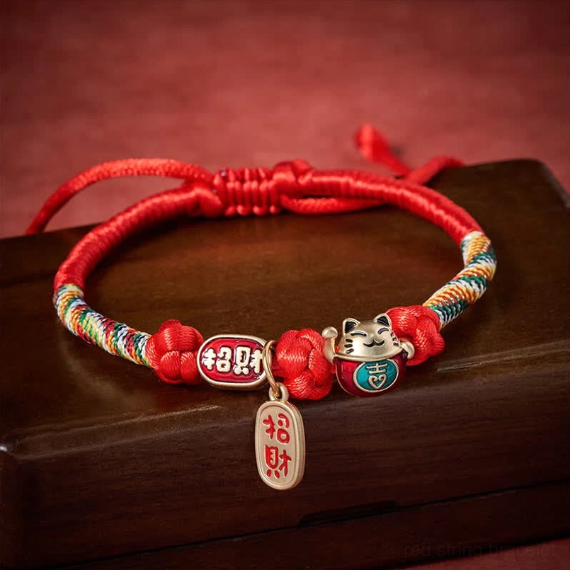 Adjustable red pet collar with sliding knot and lucky fortune pendant on wooden surface