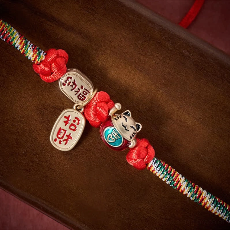 Red pet collar close-up showing naafu tag lucky cat ornament and red woven knots