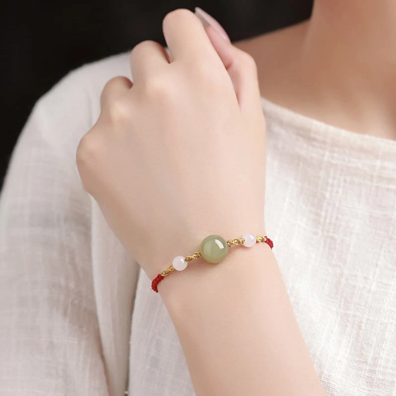 Red rope bracelet worn on wrist against light fabric background, comfort fit