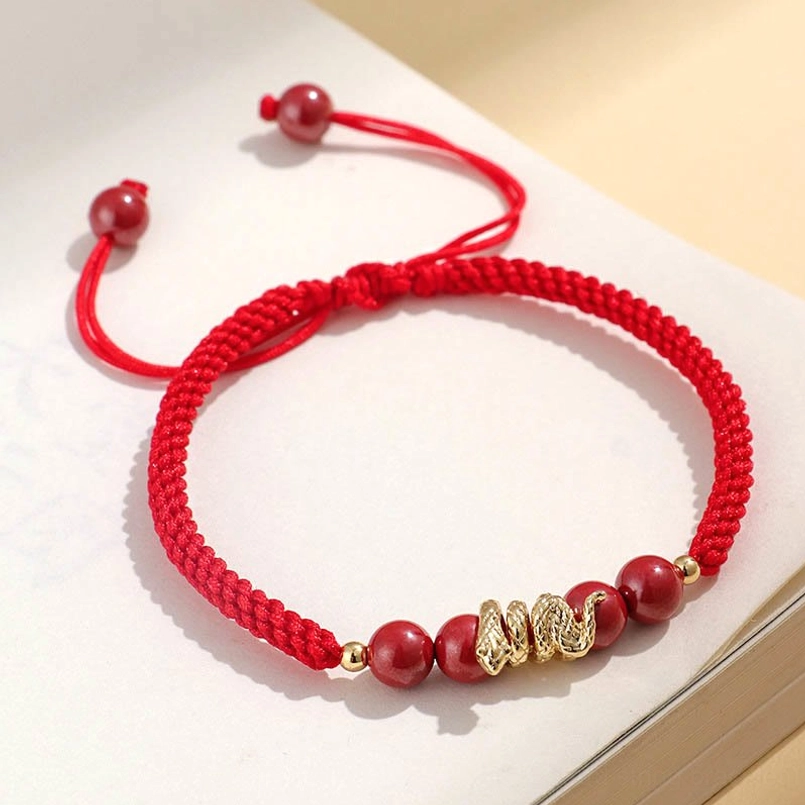 Flat lay view of braided red string Year of Snake cinnabar protection bracelet