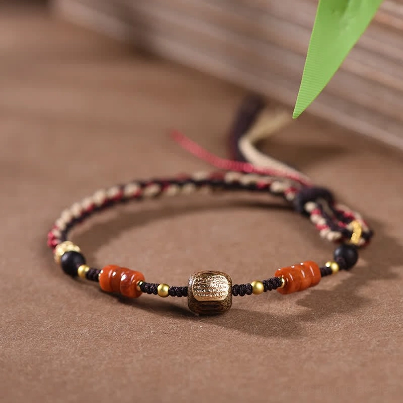 Red sandalwood blessing bracelet flat lay overhead view showing complete braided cord, agate beads and metal round decorative bead