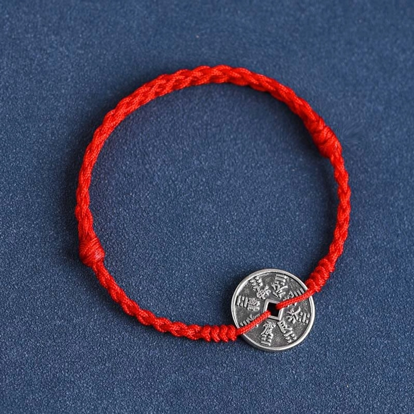 Red protective cord bracelet with adjustable knots and antique silver coin