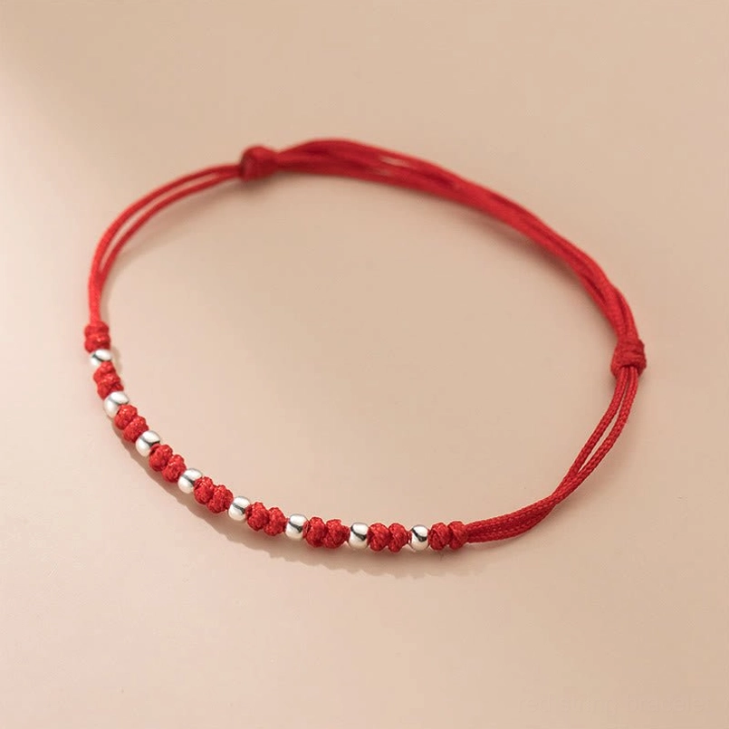 Woven red cord luck bracelet with spaced silver and red beaded details adjustable design