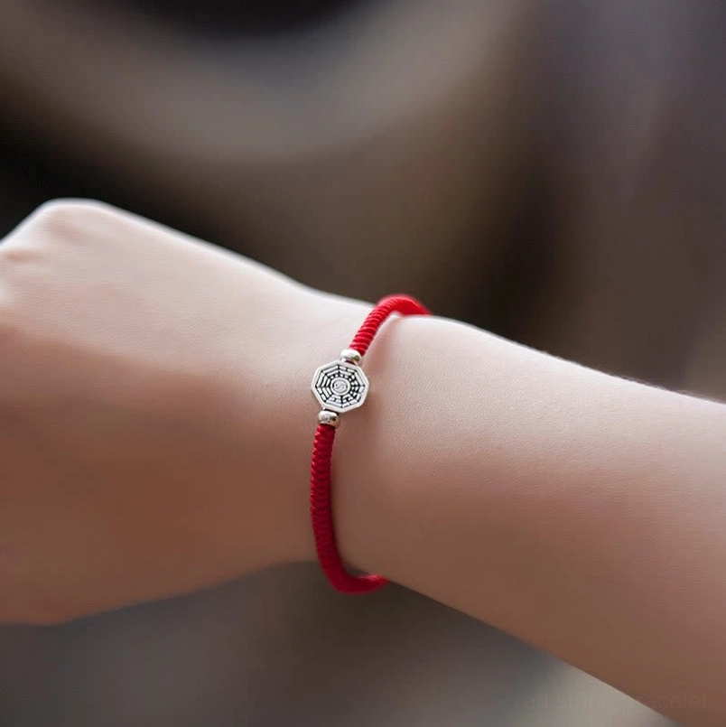 Yin yang bagua red string bracelet worn on wrist close-up detail view