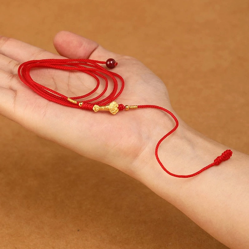 Hand-held close-up of adjustable red string belly chain demonstrating sliding knot adjustment mechanism