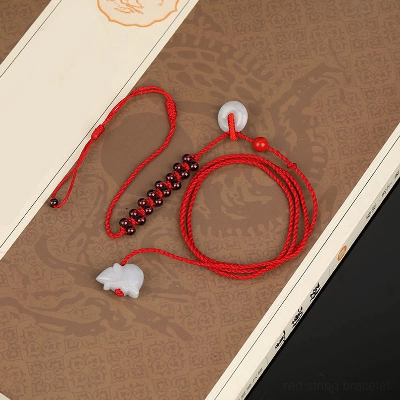 Red braided belly chain with garnet beads and jade pendant on traditional Chinese pattern paper