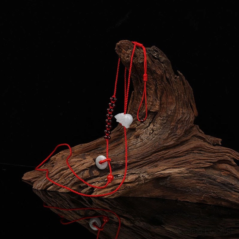 Red braided rope belly chain with garnet beads and white jade pendant on driftwood arrangement