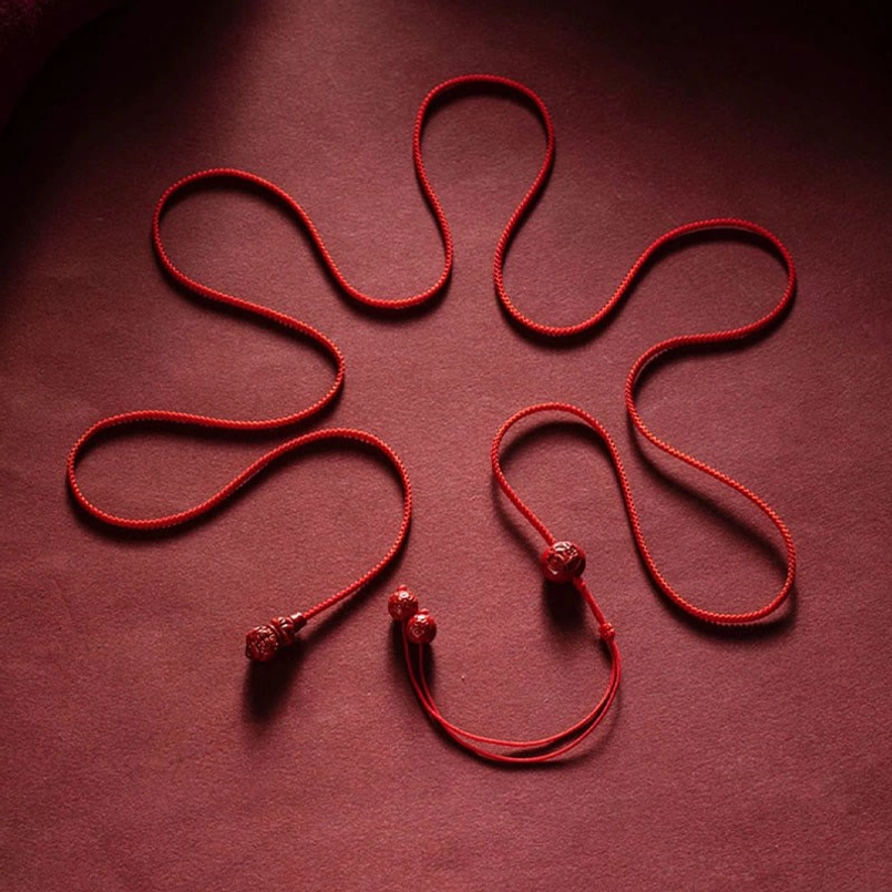 Flat lay top view of unstrung red braided cord with cinnabar junction components