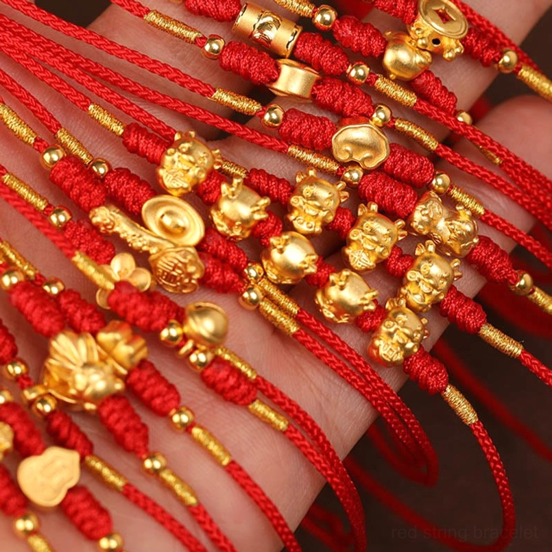 Overhead flat lay of multiple red string belly chains with various gold zodiac motifs and designs