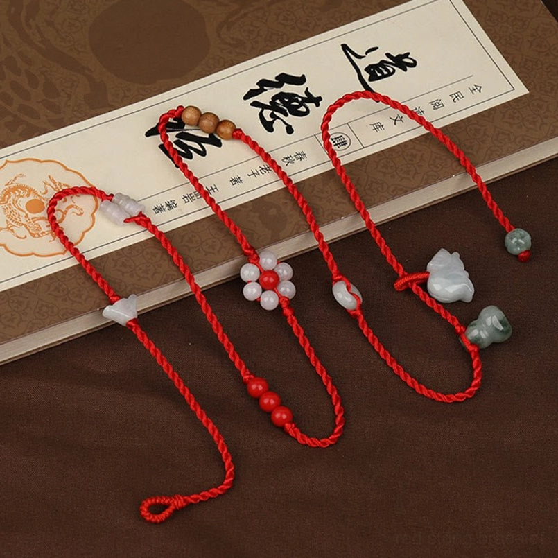 Multiple red string belly chains with jade beads and zodiac pendants on calligraphy paper background