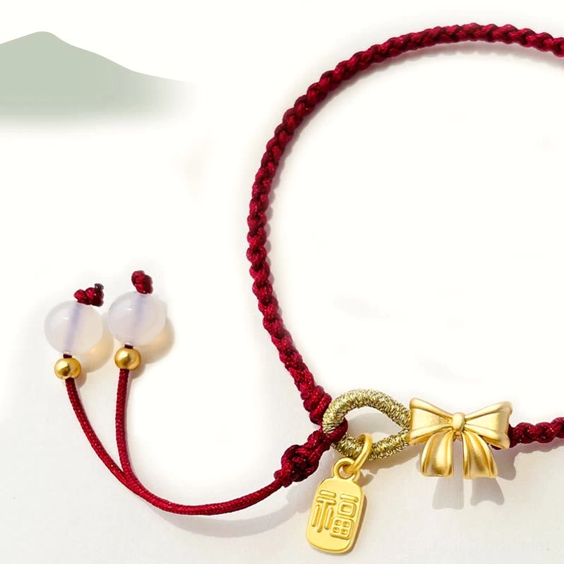 Red string lucky bracelet with gold bow knot charm, Fu character tag, and adjustable white bead tassel