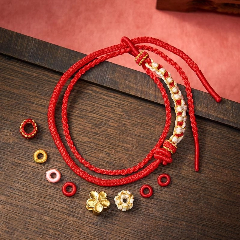 Red string bracelet components including beads and flower charms display