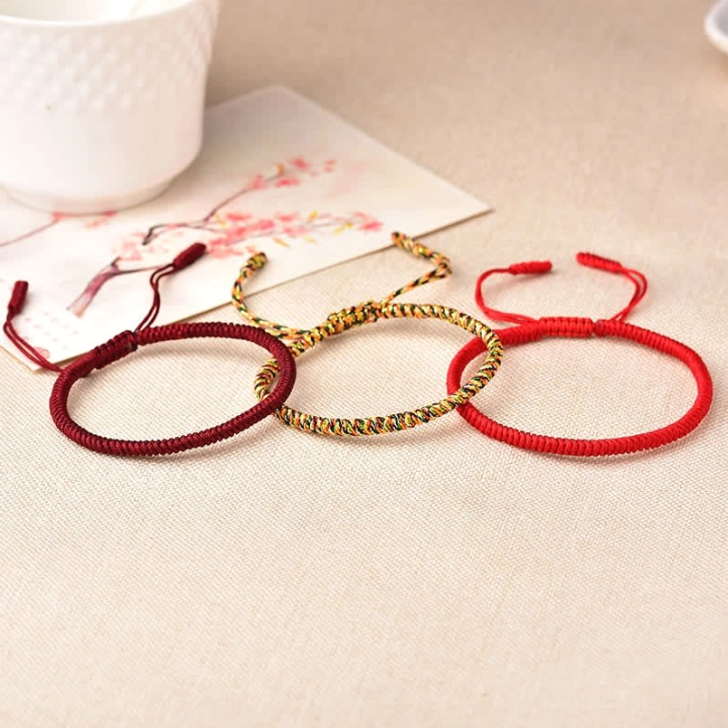 Three adjustable red string bracelets flat lay with wine red gold and crimson color options