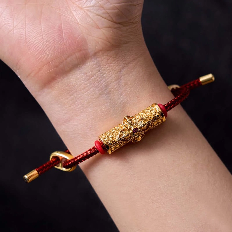 Adjustable red string bracelet with copper flower charm showing knot clasp system