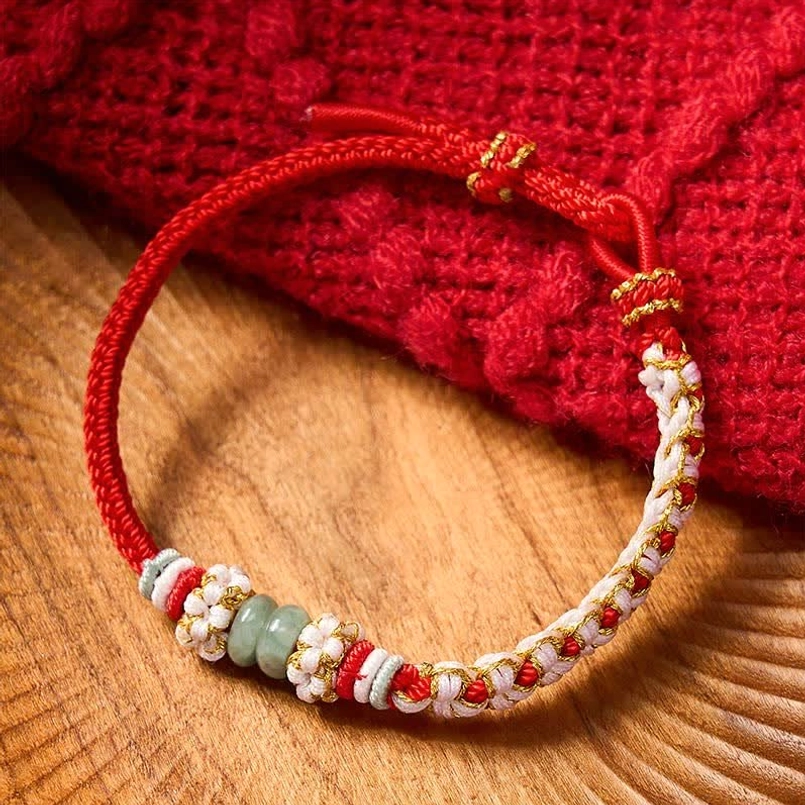 Red bracelet with adjustable knot closure shown at eye level on wooden table