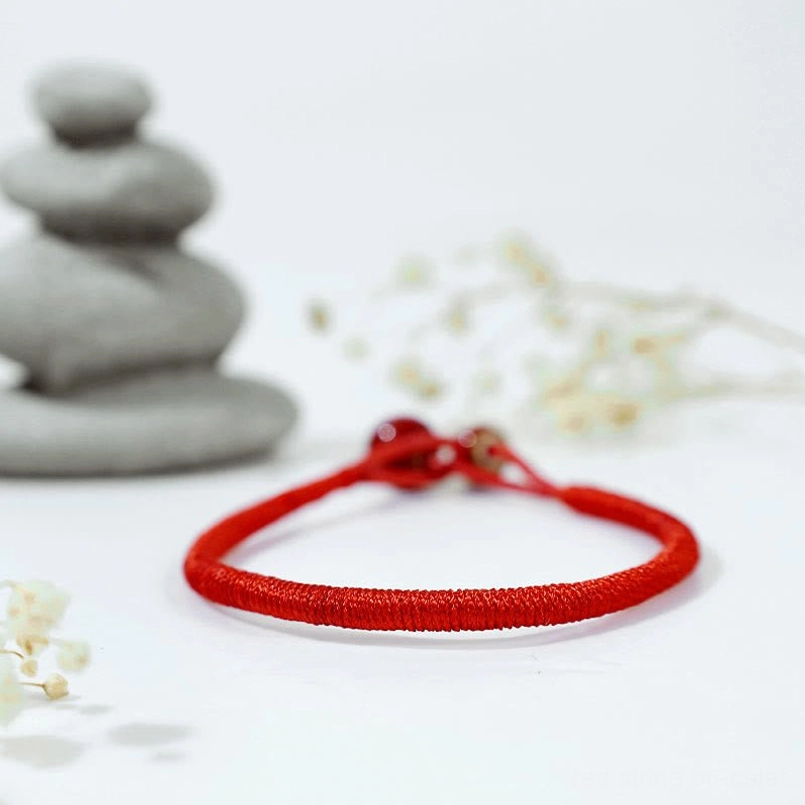 Rear three-quarter view of adjustable red string bracelet showing sliding knot closure