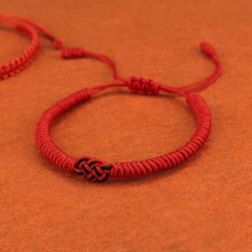 Tibetan red string bracelet with adjustable knot showing how to fit various wrist sizes