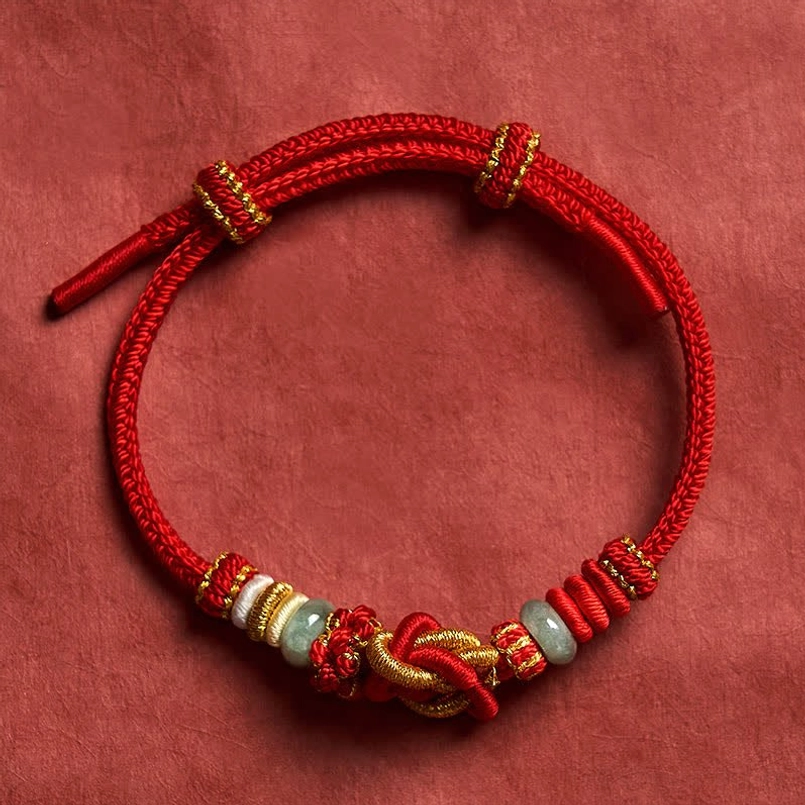 Adjustable red braided jade bracelet with slide knot flat lay on red background