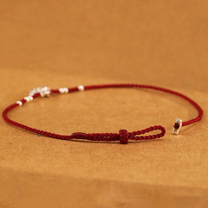 Adjustable red string bracelet side view flat lay showing silver beads and adjustable knot design