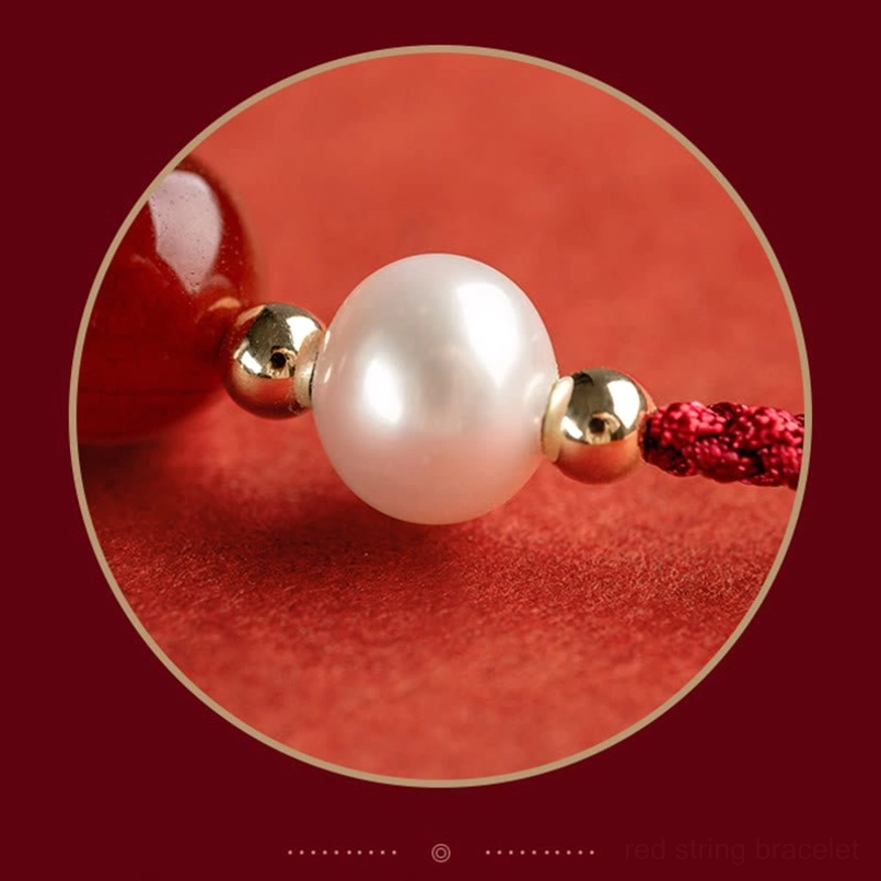 Close-up macro view of red string bracelet beads showing polished red agate, lustrous pearls and gold spacers