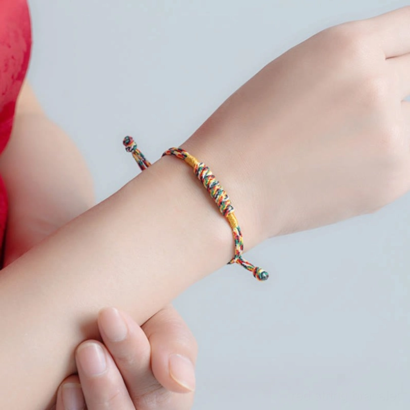 Lucky knot red string bracelet placed next to small blessing charm decor