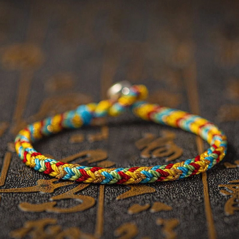 Close-up side view of woven multicolored red string bracelet showing braided texture