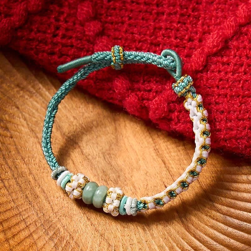 Red Chinese knot bracelet close-up showing intricate braiding and jade