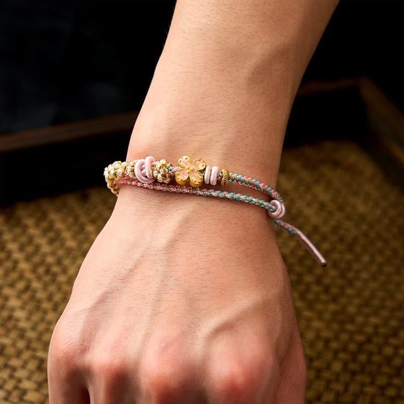 Red string bracelet with multiple charm options and decorative elements