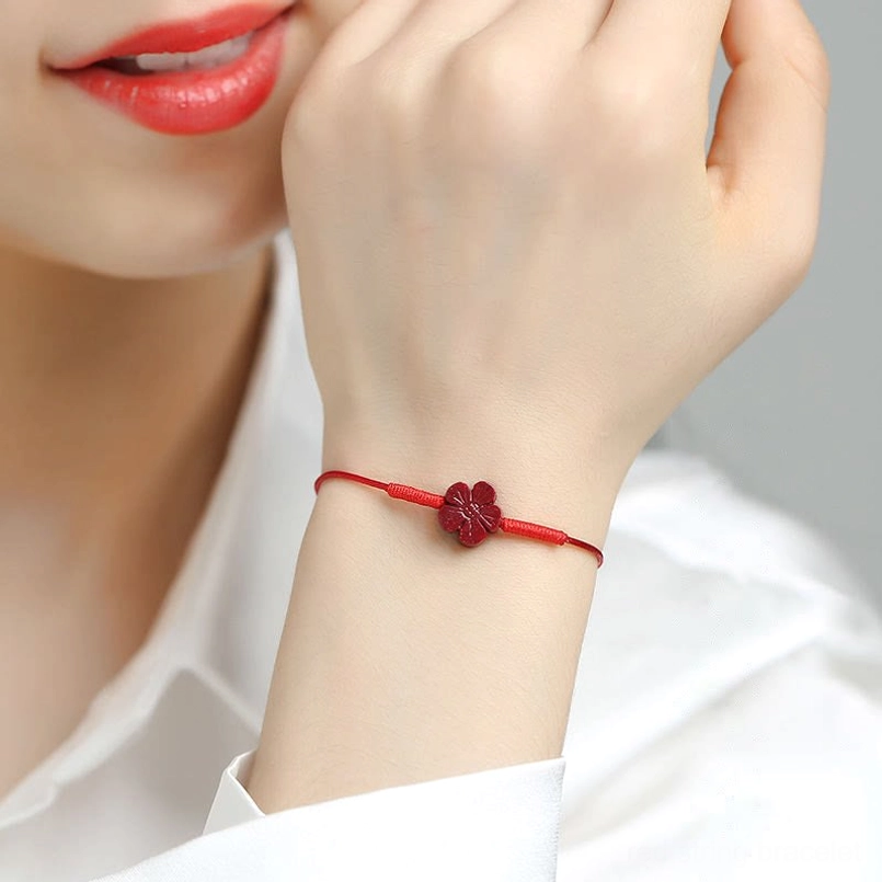 Red cord bracelet with cinnabar plum blossom charm side view