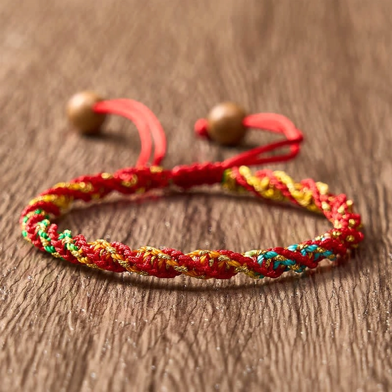 Handcrafted ethnic red string bracelet displaying blue yellow green threads, flat lay