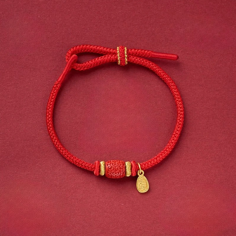 Red string bracelet with solid copper barrel bead and gold drop pendant on dark background