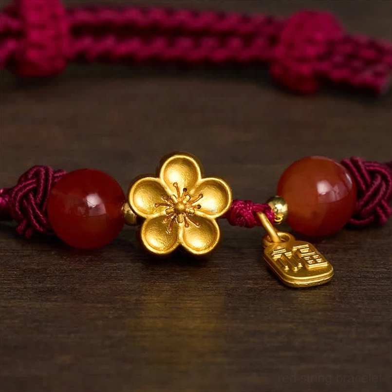 Macro close up of copper peach blossom charm and fu pendant on red string bracelet