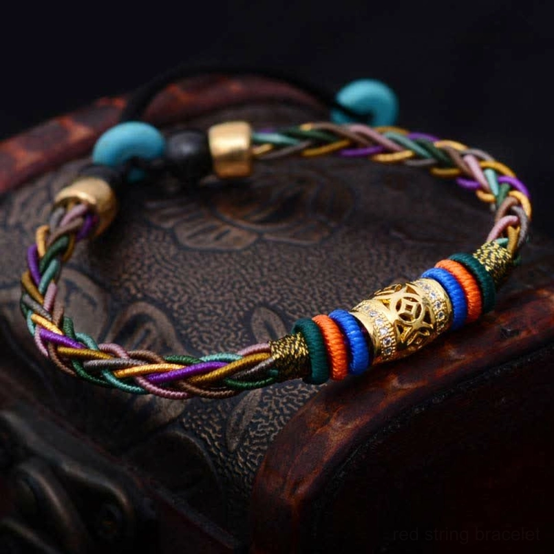 Lucky red string bracelet with copper coin and turquoise beads on vintage leather case top view