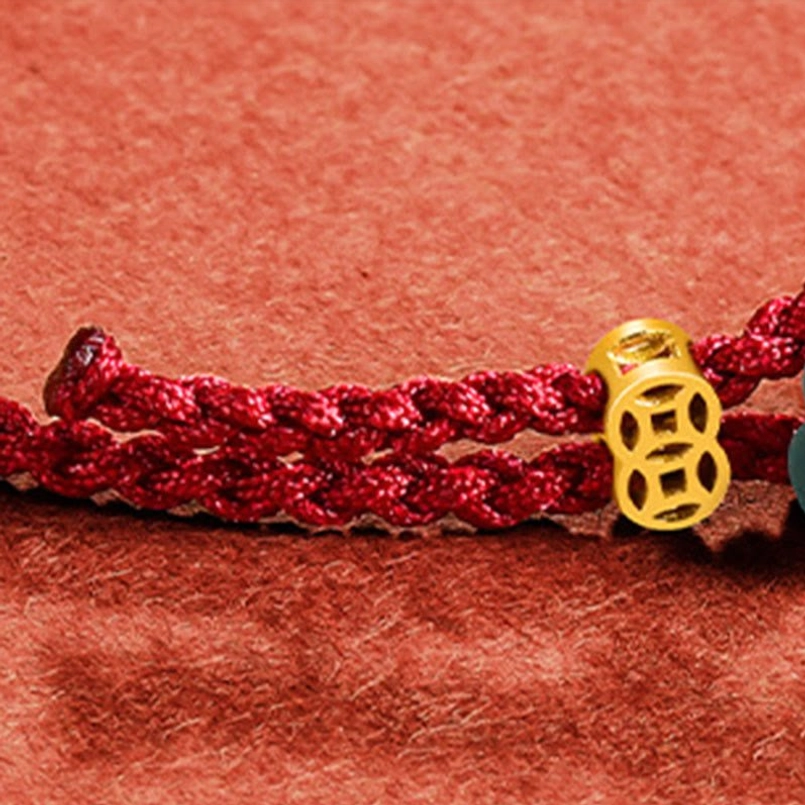 Close-up of braided red rope cord texture with gold copper coin charm detail