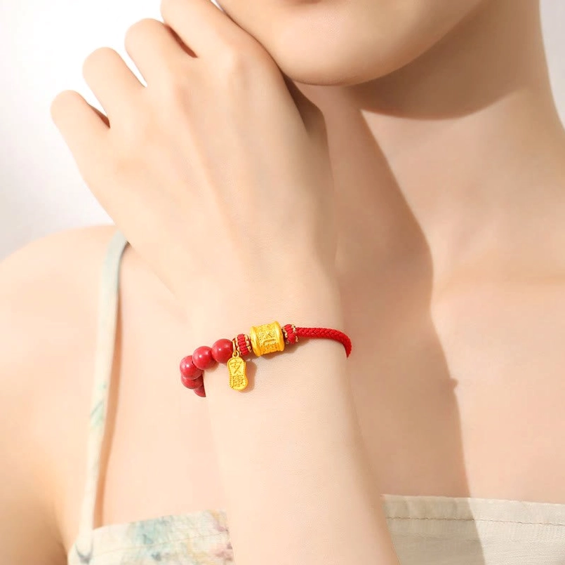 Red string protection bracelet with gold engraved charm, worn on female wrist for daily spiritual practice