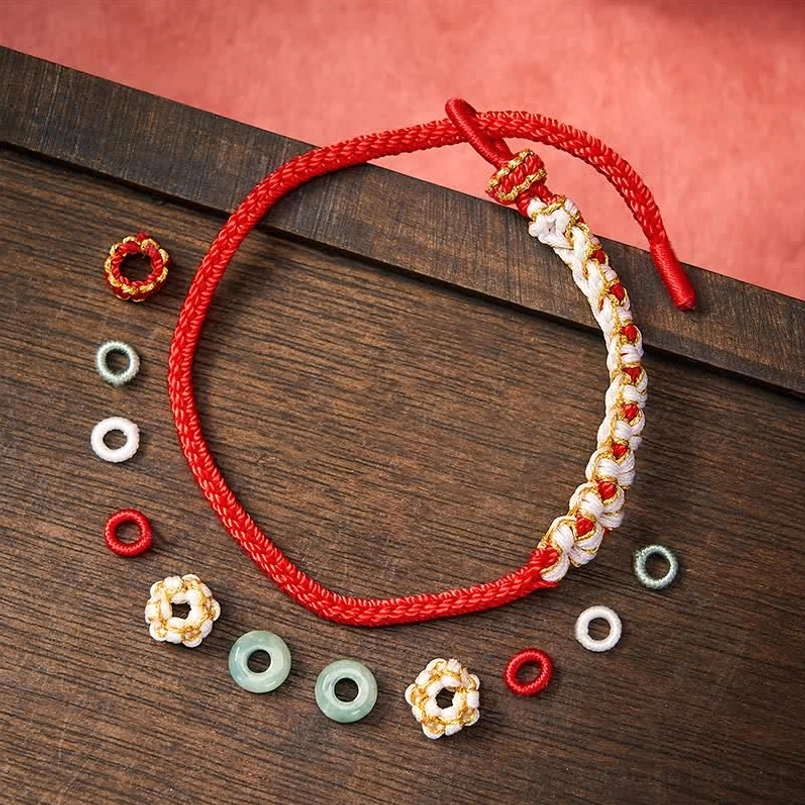 Handmade red string bracelet flat lay showing adjustable knot and replacement jade beads