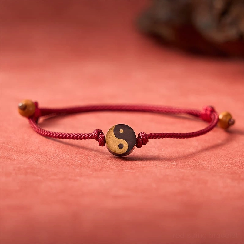 Red string adjustable Yin Yang bracelet flat lay on red background