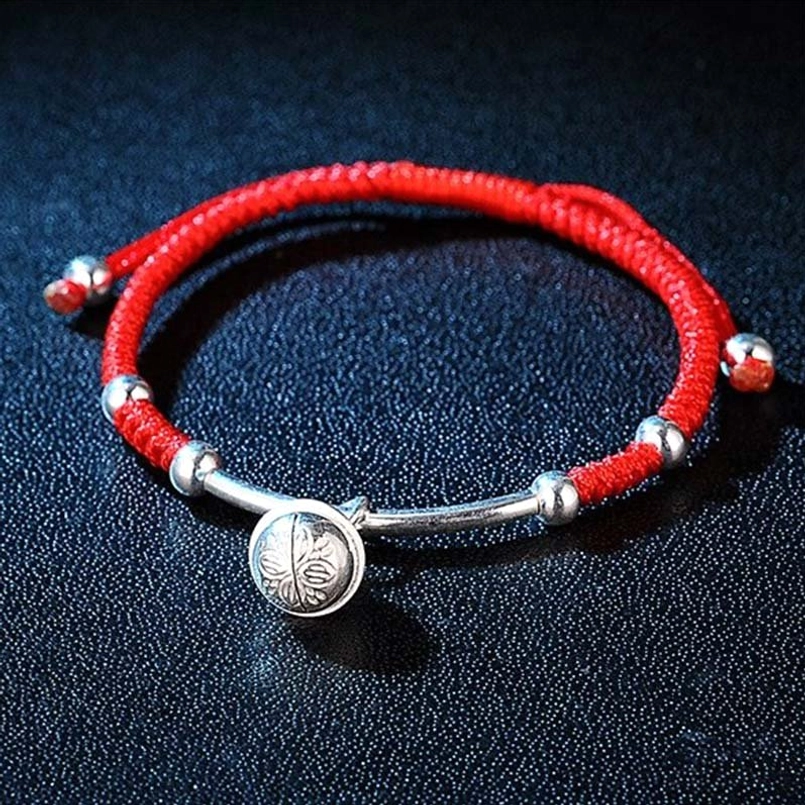 Handmade red string bracelet flat lay with double-layer braided cord and silver pendant