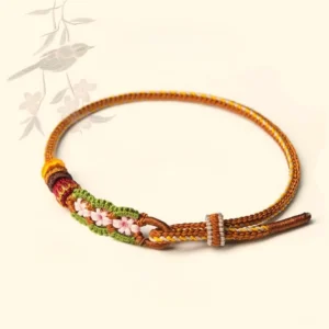 Hand-woven red string bracelet with pink floral knots and adjustable closure on minimalist oriental background