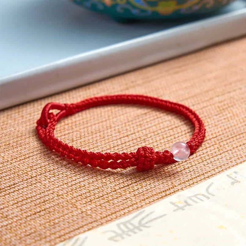 Red string balance bracelet with gemstone accent close-up detail view