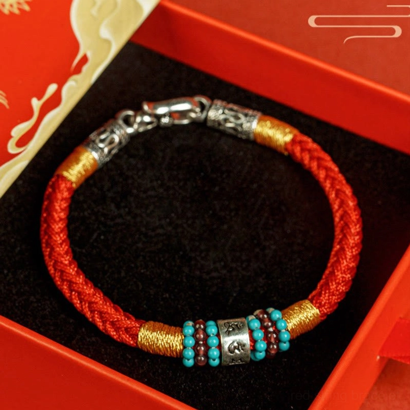Red string Tibetan bracelet placed inside luxury red gift box with black flannel lining