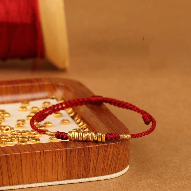 Red string bracelet with 999 gold beads wooden display