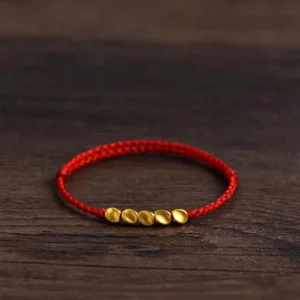 Red string braided protection bracelet with gold beads oblique view