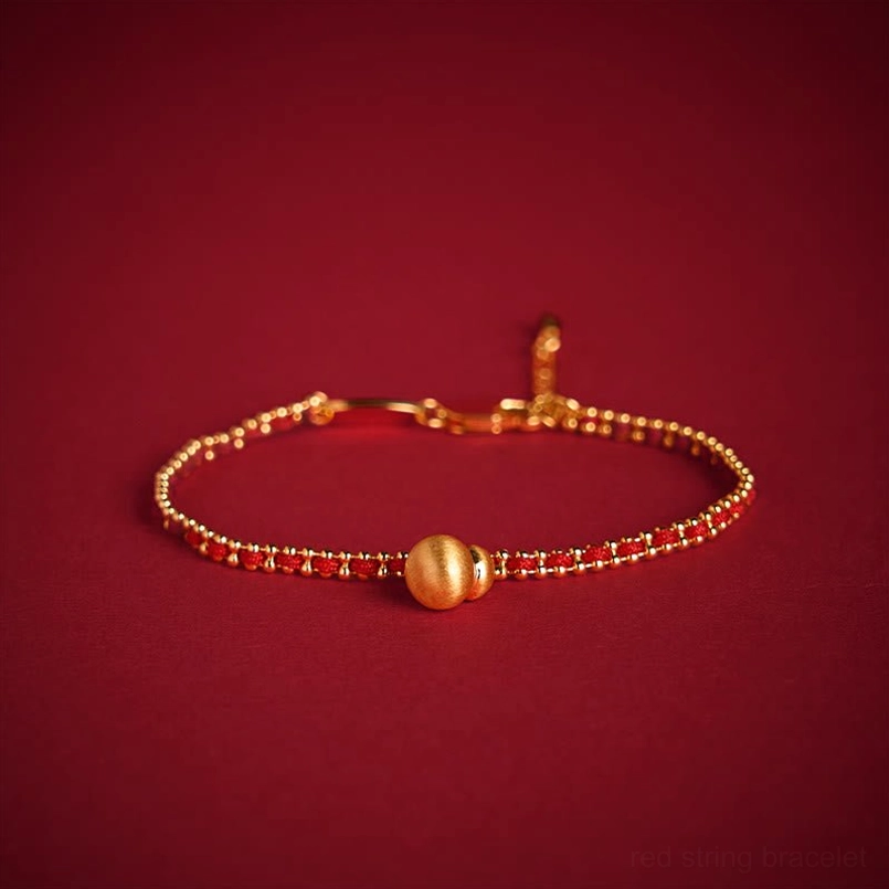 Red cord bracelet with brushed gold round pendant and copper spacer beads flat lay